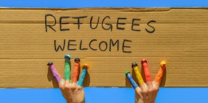 Refugees welcome - Hände mit bunten Fingern halten ein Pappschi